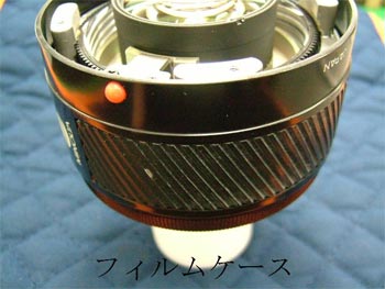 カメラ分解手順９：レンズとフィルムケースを離れないよう押さえ、ひっくり返す