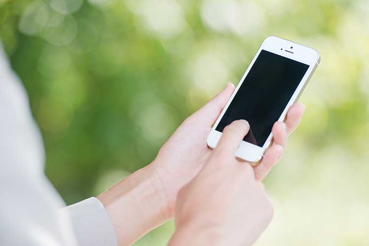 iPhoneのタッチパネルを操作している手元